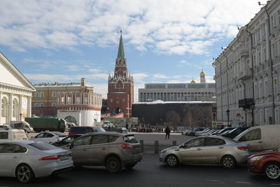 Cars on street by buildings against sky in city