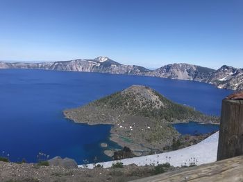 Scenic view of lake and mountains against clear blue sky