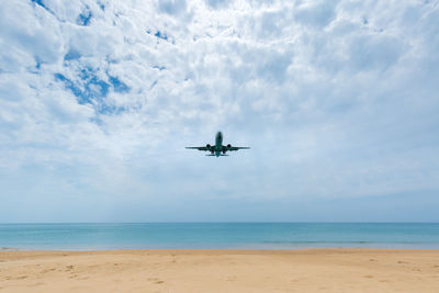 Airplane flying over sea against sky