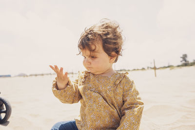 Cute boy on beach against sky