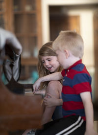 Cute siblings playing piano at home