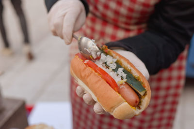 Midsection of person preparing hot dog at market stall