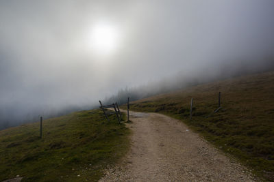 Road amidst trees against sky during foggy weather