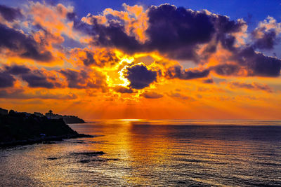 Scenic view of sea against dramatic sky during sunset