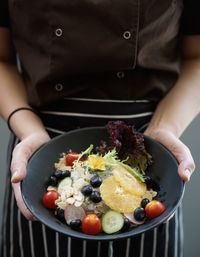 Midsection of chef holding bowl while standing outdoors