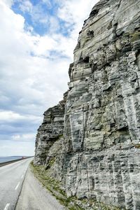 Low angle view of rock formation on road against sky