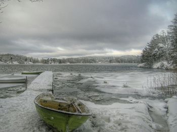 Boats in river against cloudy sky