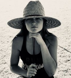 Portrait of woman wearing straw hat sitting on beach