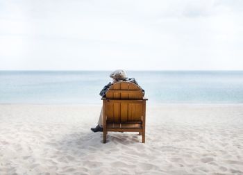 Rear view of people sitting on chair on beach
