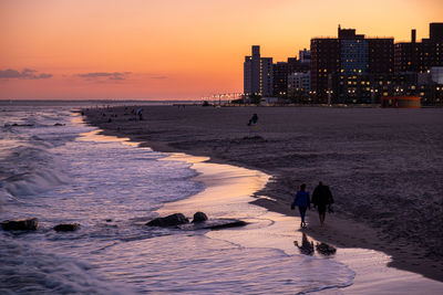 People on beach against sky during sunset