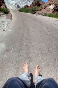 Low section of man levitating over road against mountains