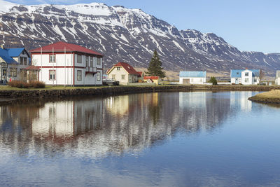 Buildings and landscape reflected in the water of fjord