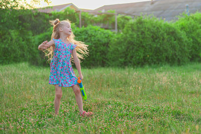 Little girls play in the summer on a green meadow with water pistols