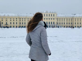 Woman looking away while standing building during winter