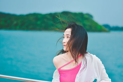 Young woman looking at sea against sky