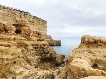 Rock formations on beach against sky