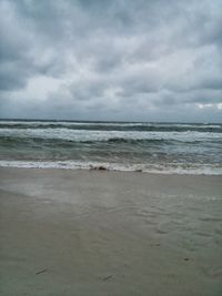 Scenic view of beach against cloudy sky