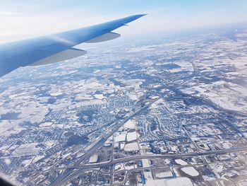 Aerial view of airplane wing over landscape against sky