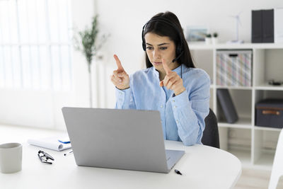 Young woman using mobile phone while sitting on table