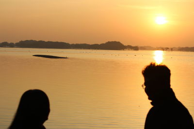 Silhouette people on beach against clear sky during sunset