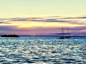 Silhouette boat sailing in sea against sky during sunset