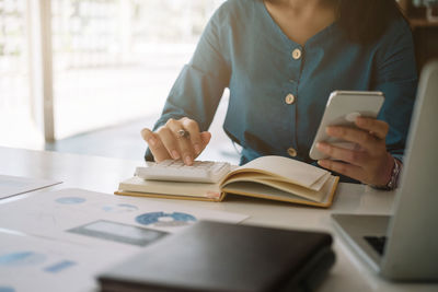 Midsection of woman using mobile phone at office