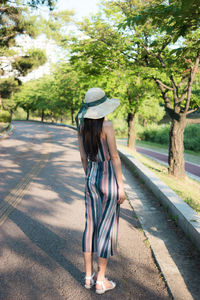 Rear view of woman with umbrella on road