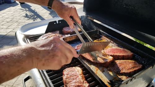 Close-up of man preparing food on barbecue grill