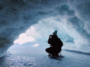 Woman in crouching in frozen cave