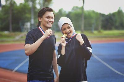 Happy athletes with medals standing on sports track