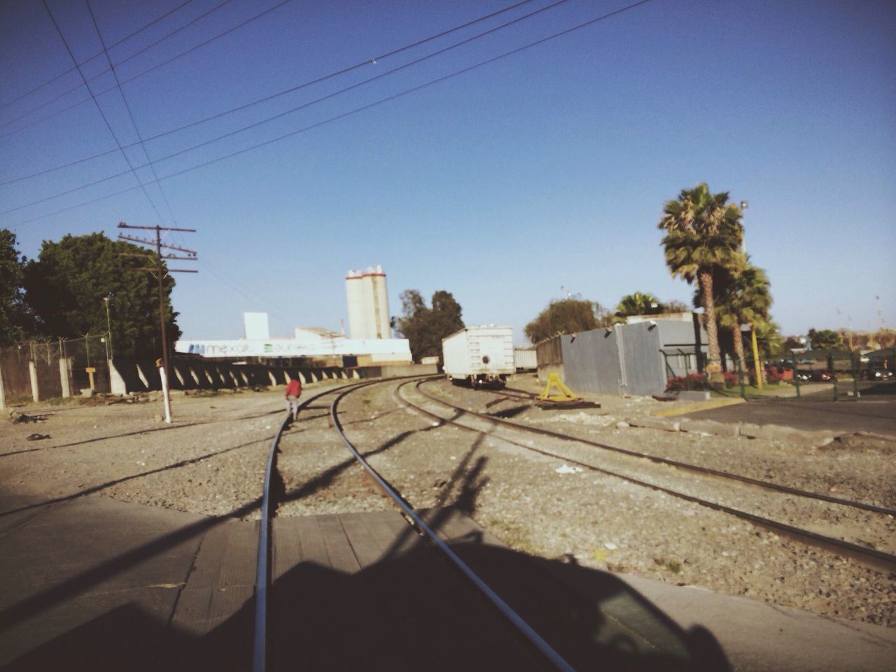 clear sky, building exterior, built structure, architecture, transportation, street, sunlight, road, power line, tree, blue, shadow, house, day, copy space, mode of transport, city, car, land vehicle, outdoors