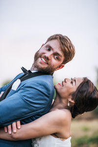 Smiling newlywed couple embracing on field