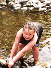 Portrait of girl pulling rock by stream