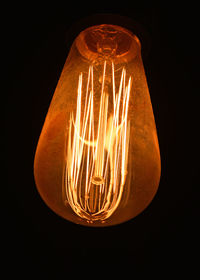 Close-up of illuminated light bulb against black background