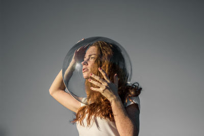 Portrait of woman holding hands against white background