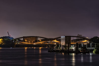 Illuminated bridge over river against sky at night