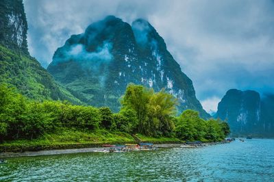 Scenic view of lake by mountains against cloudy sky