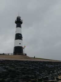 Lighthouse on beach against sky