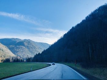 Road leading towards mountains against sky