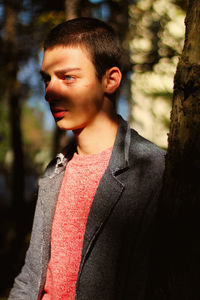 Portrait of mid adult man looking away while standing on tree trunk