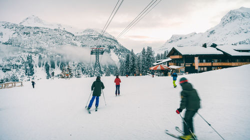 People skiing on snow covered mountain against sky