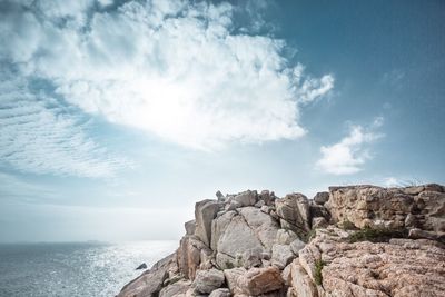 Scenic view of cliff by sea against sky