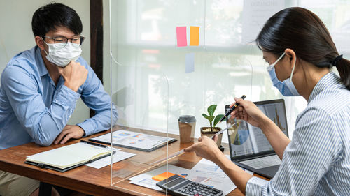 Business people wearing mask having discussion in office