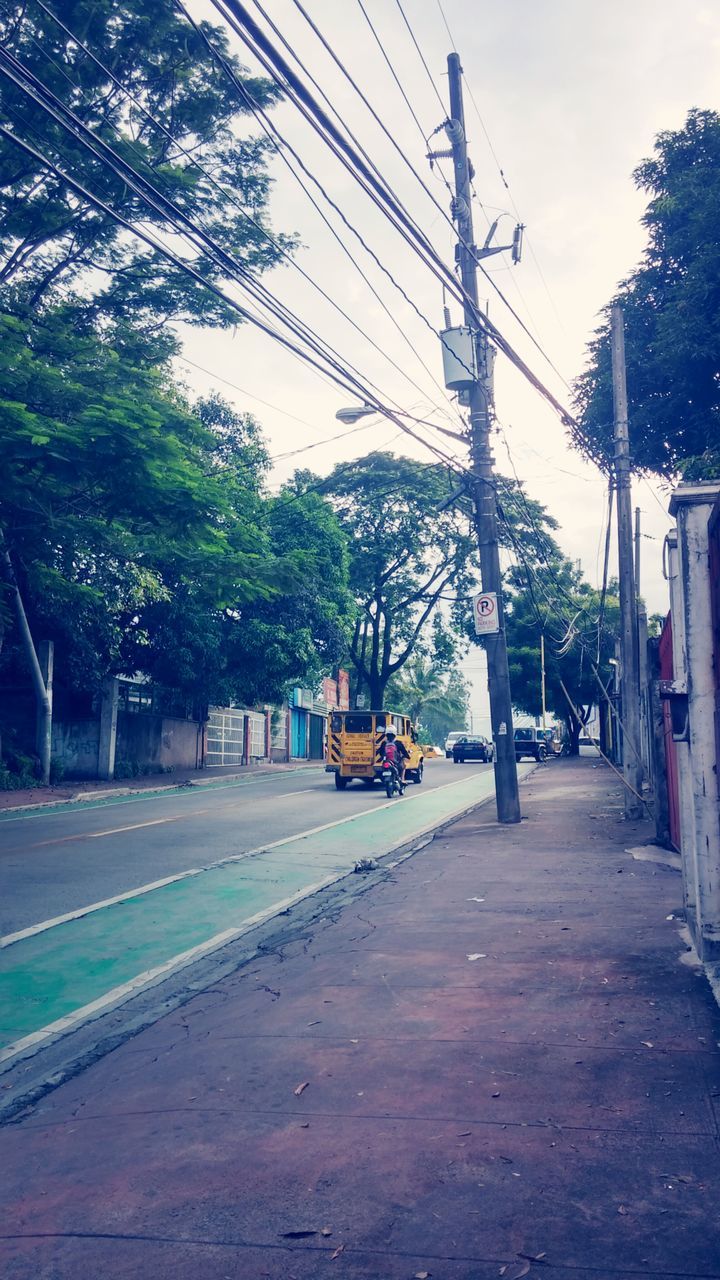 power line, tree, electricity pylon, transportation, road, street, the way forward, cable, power supply, electricity, sky, building exterior, built structure, architecture, car, power cable, mode of transport, clear sky, outdoors, diminishing perspective