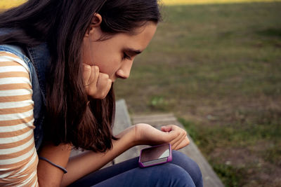 Side view of young woman using mobile phone