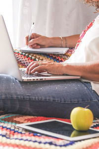 Midsection of woman using laptop at home