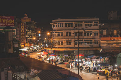 People on illuminated street amidst buildings in city at night