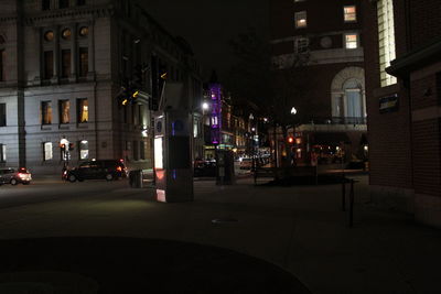 Illuminated road by city against sky at night