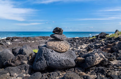 Rocks on shore by sea against sky