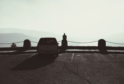 Silhouette man on car against sky